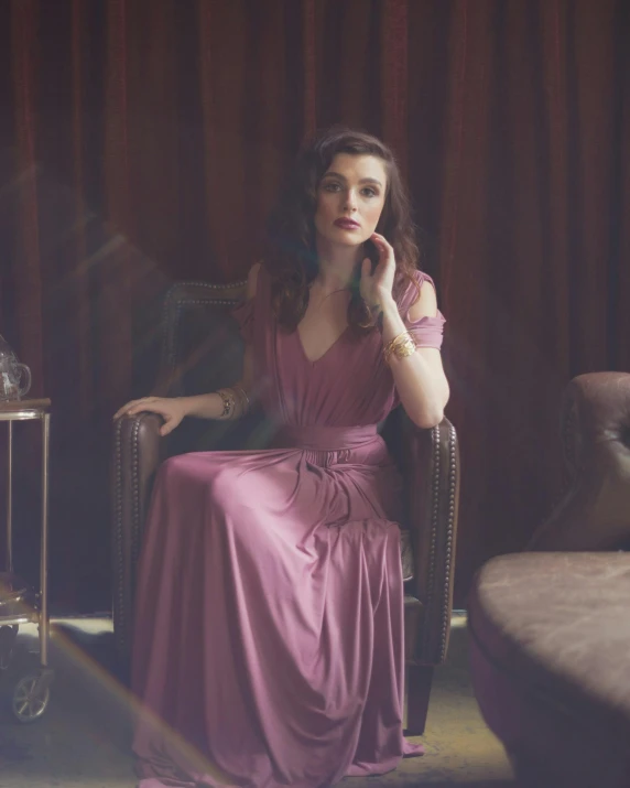 a woman is wearing a purple dress while sitting in a chair