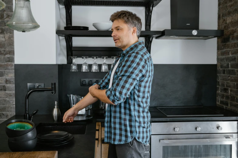 a man in blue plaid shirt standing at counter in kitchen