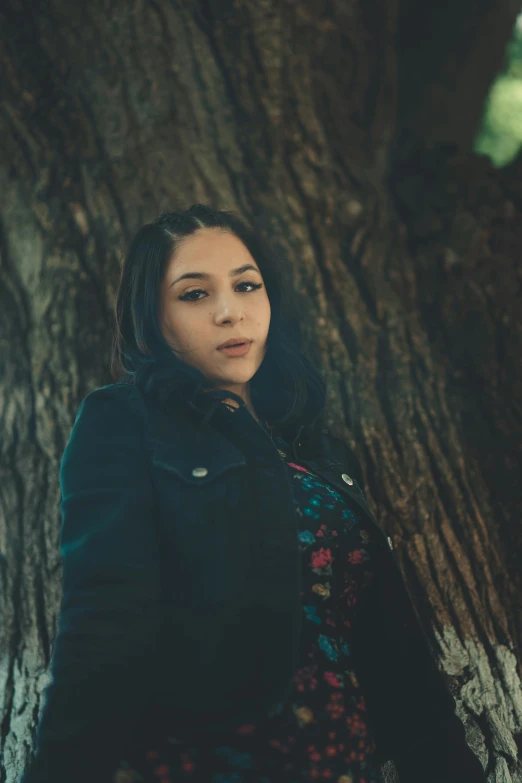 a woman poses for a po next to a tree