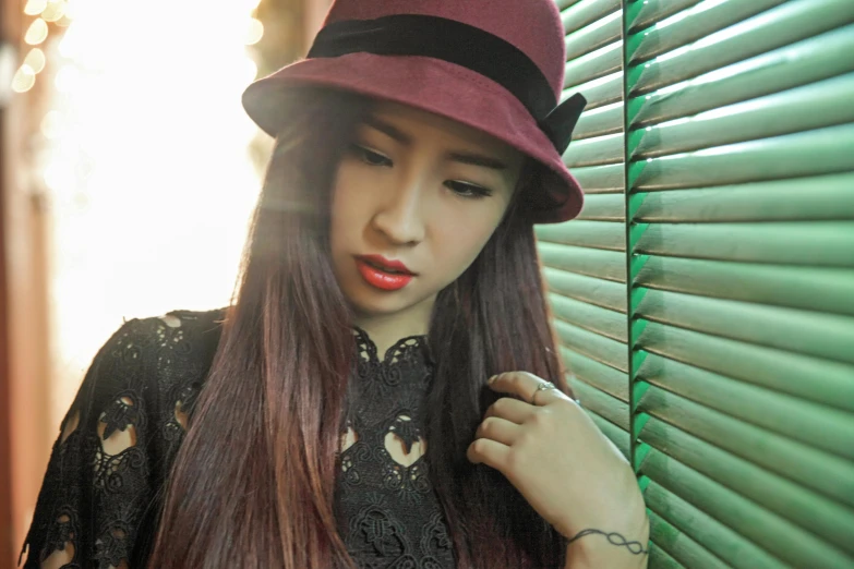 a woman in black shirt and hat near blinds