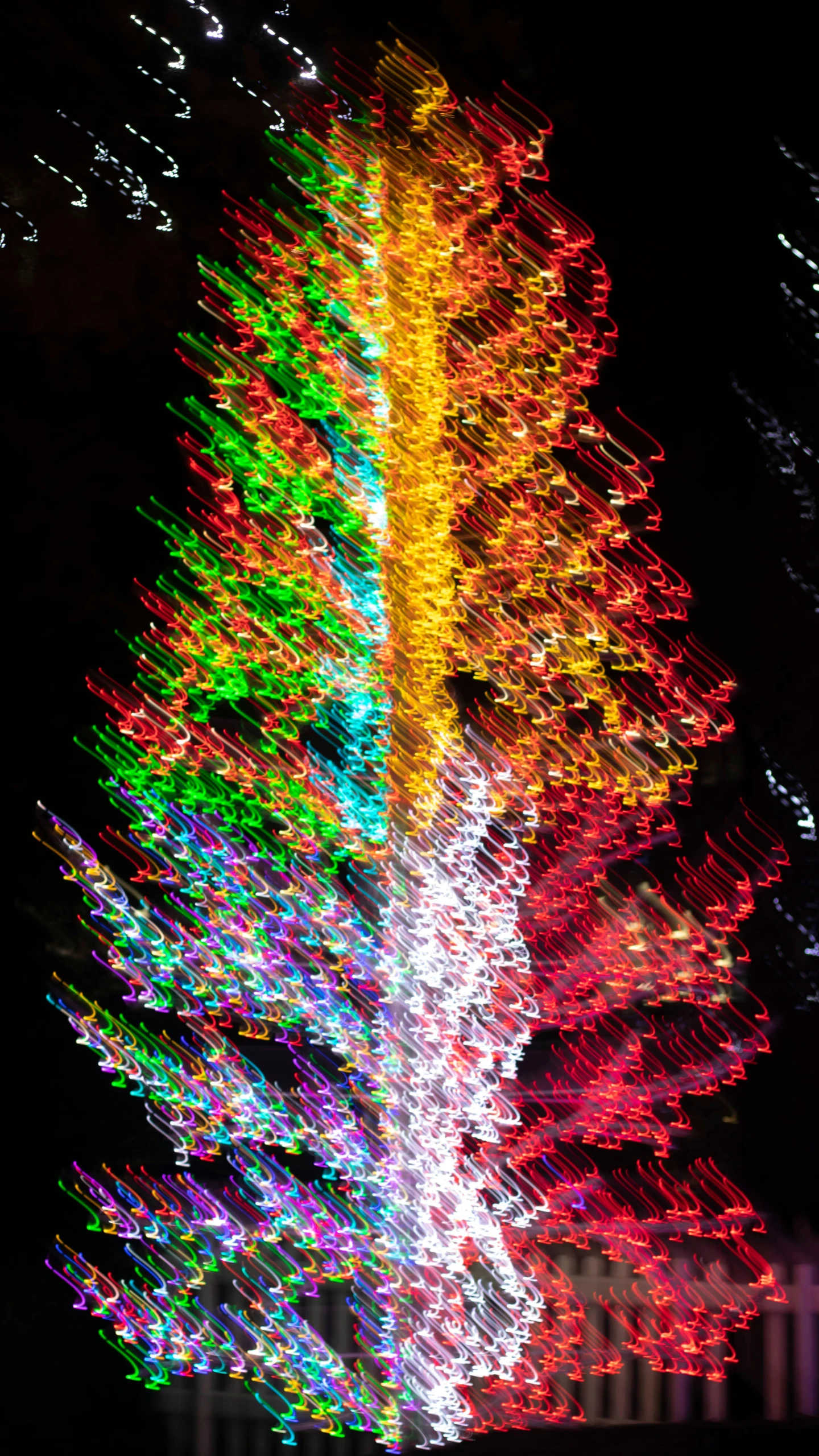 multi - colored lights are set up at the top of a tall tree