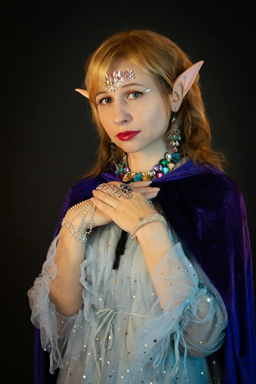 a woman dressed as an elf wearing a costume and a blue cape