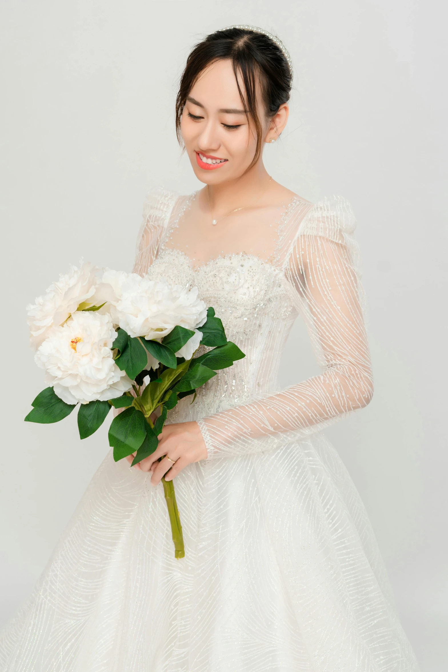 an asian woman in wedding gown holding flowers