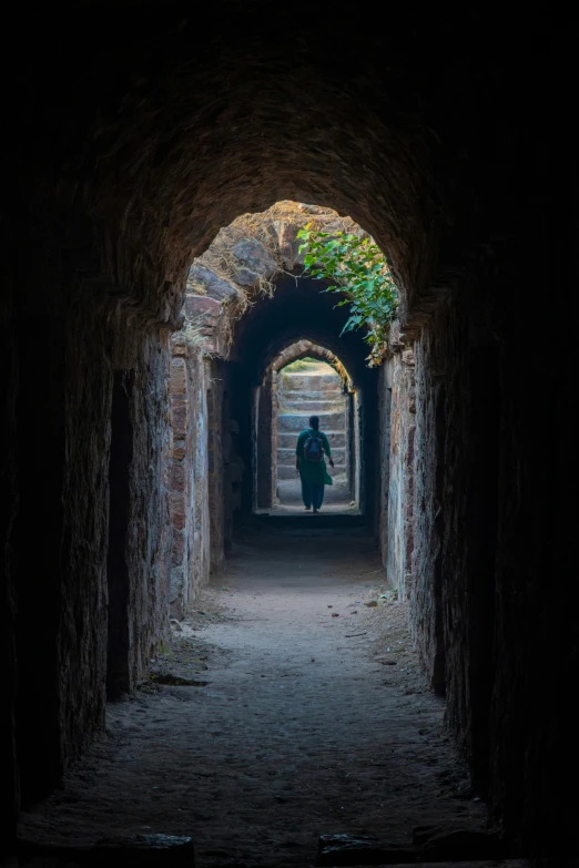 a woman walks out of an old tunnel