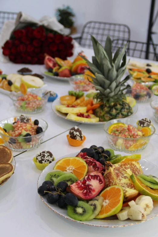 a white table with various kinds of fruits on plates