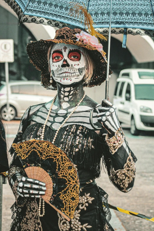 a woman dressed up in a dia de los muert costumes holds an umbrella while walking