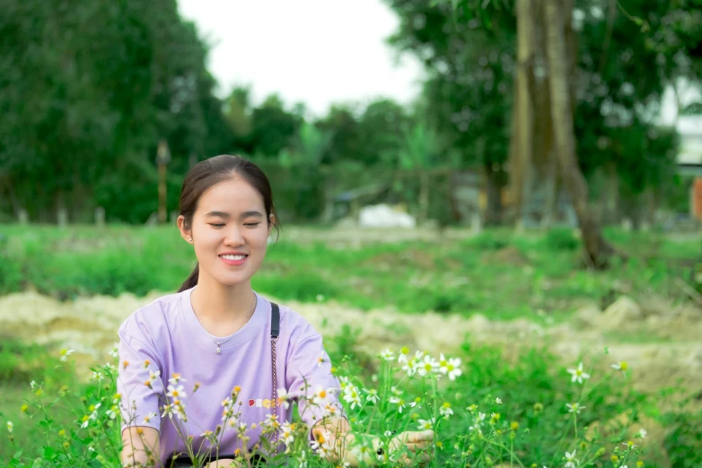 an asian girl smiles while sitting in grass