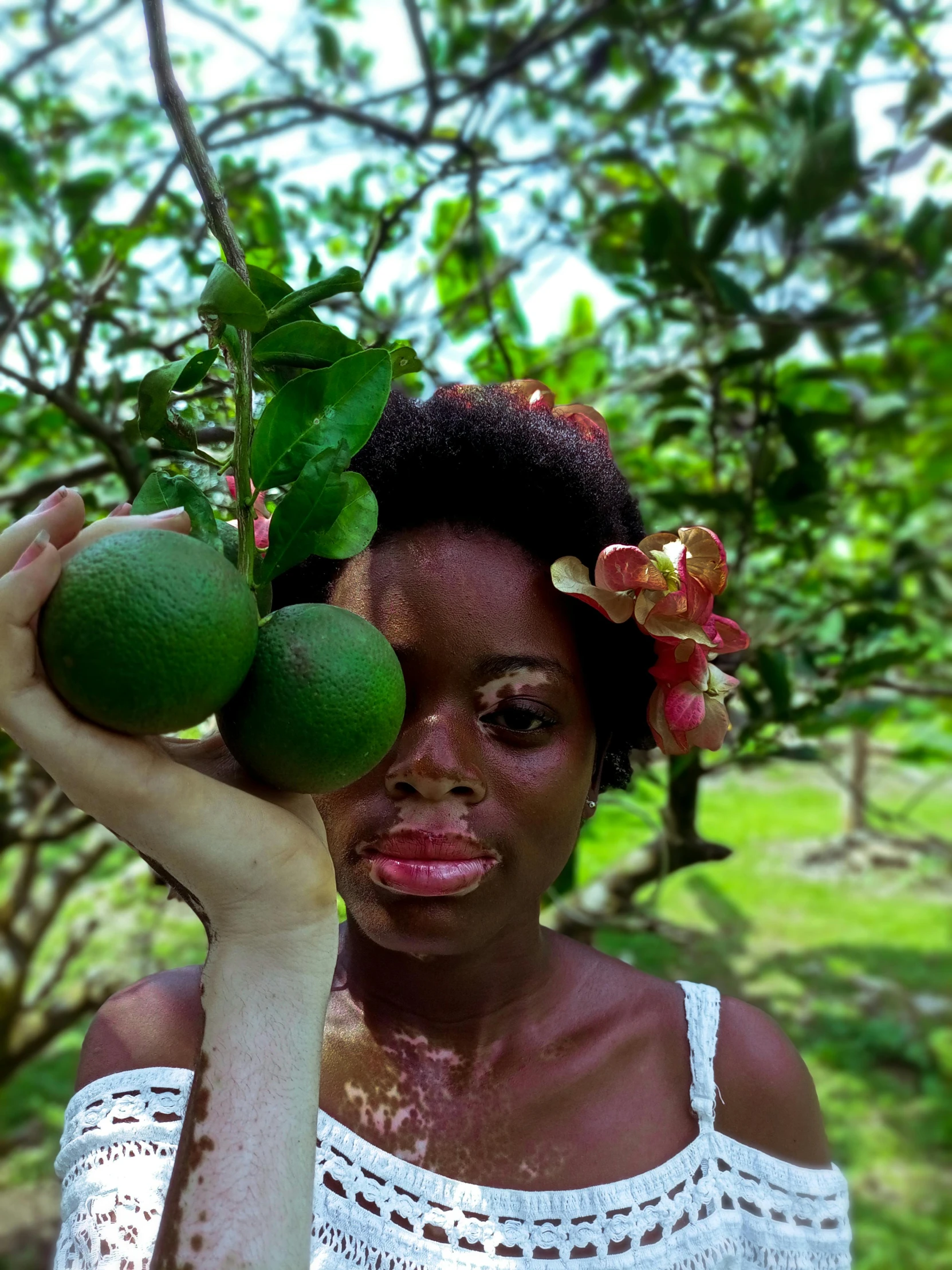 a woman in a white top holds up a green fruit