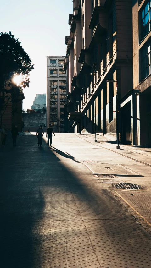 people walking in an empty city street at sunset