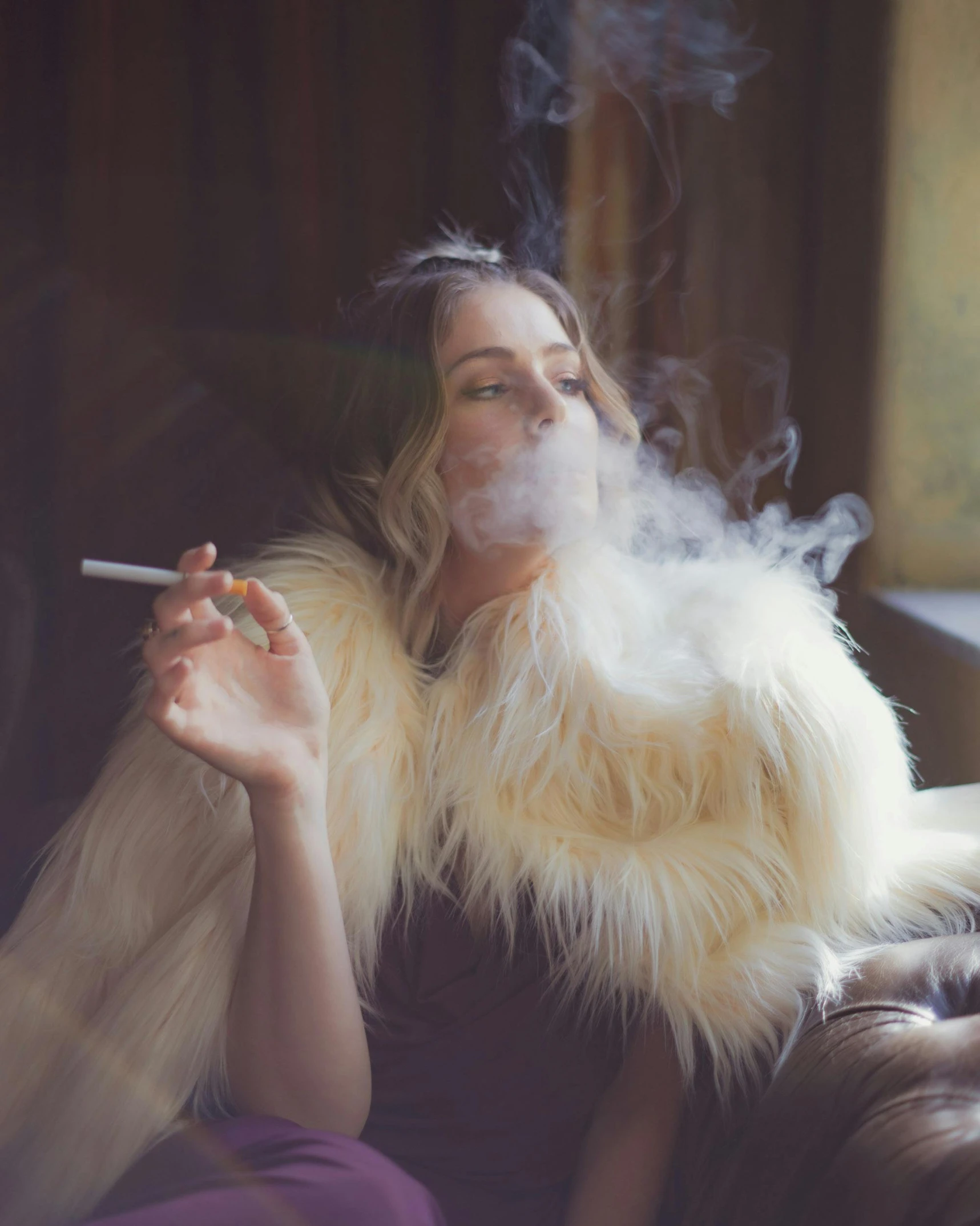 a woman sitting on a couch smoking a cigarette