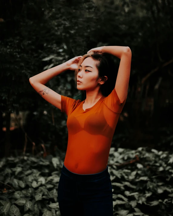 woman with long hair, wearing dark jeans and orange shirt