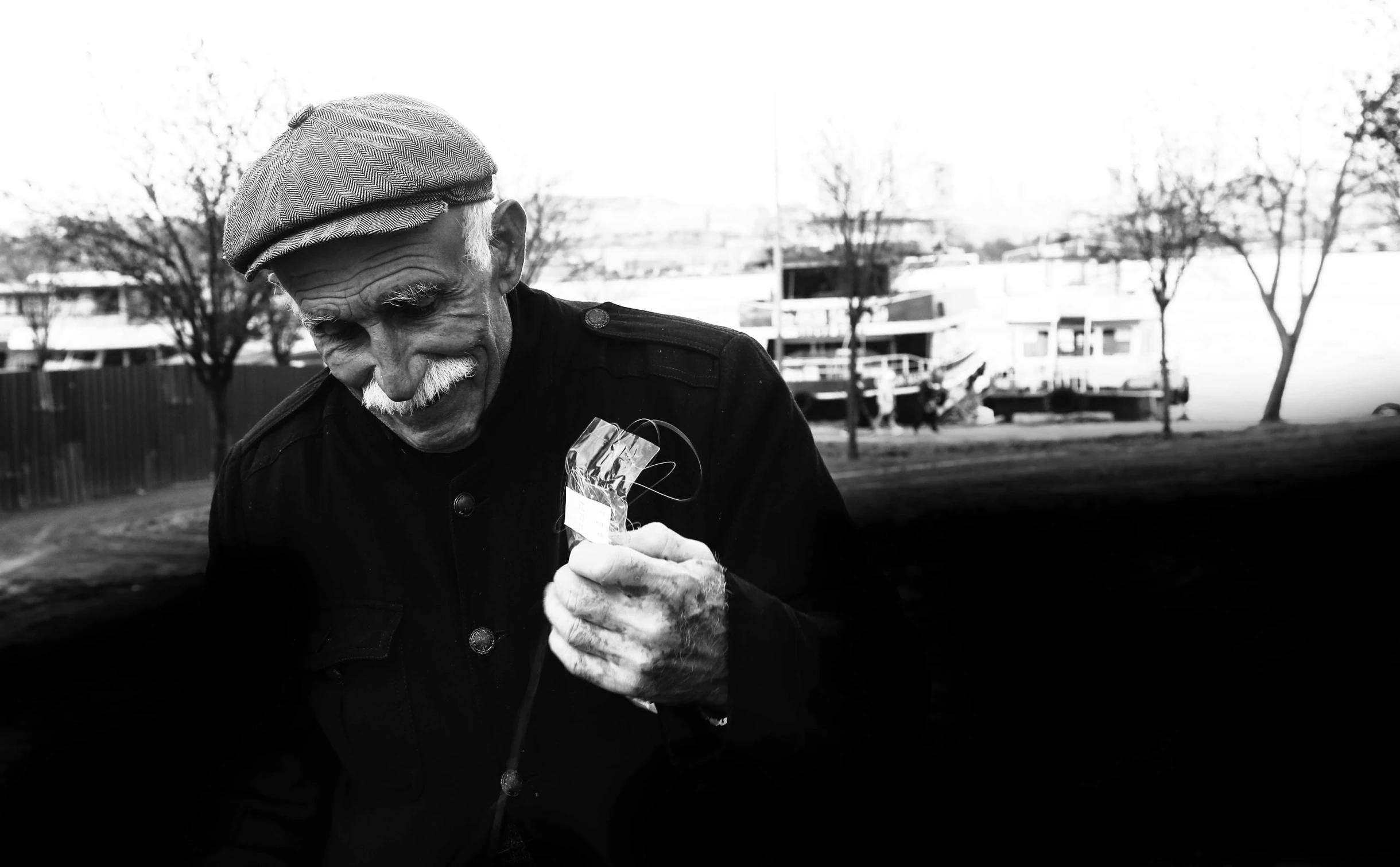 an older man smiles while looking at a cell phone