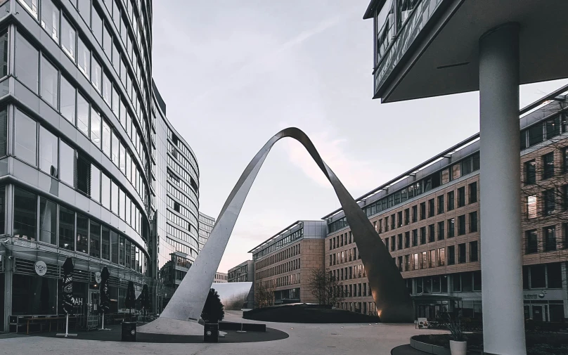 a large arch stands next to buildings in a city