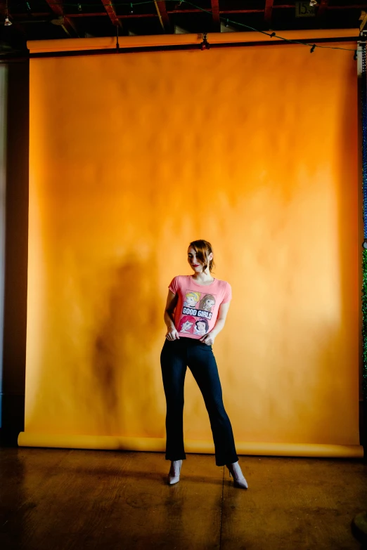 the dancer poses against an orange wall with a yellow background