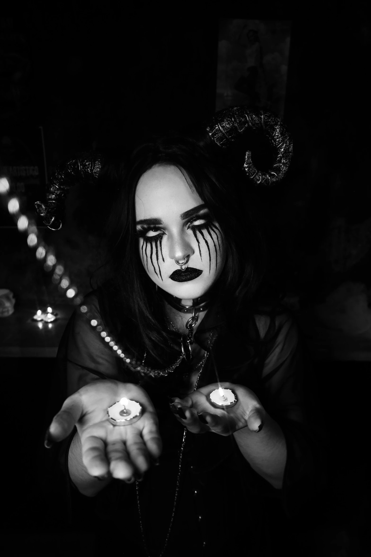 a woman wearing scary makeup and holding lit candles