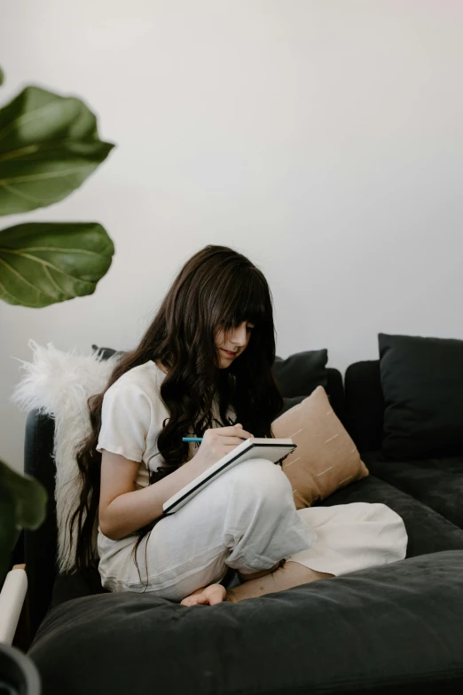a woman sitting on a couch with a notebook and pen