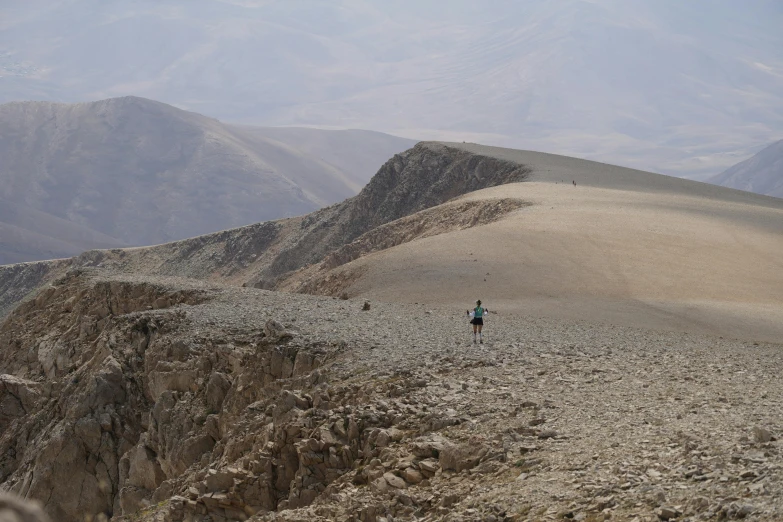 two people walking on a rocky slope towards the camera