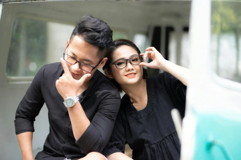 a young couple who is holding hands on their heads, both looking at a small camera