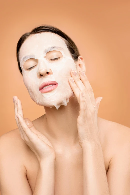 the woman with white face mask on her face holds hands on her side