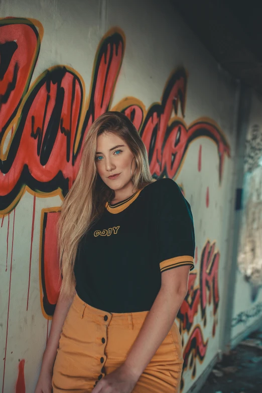 a woman is standing in front of a graffiti covered wall