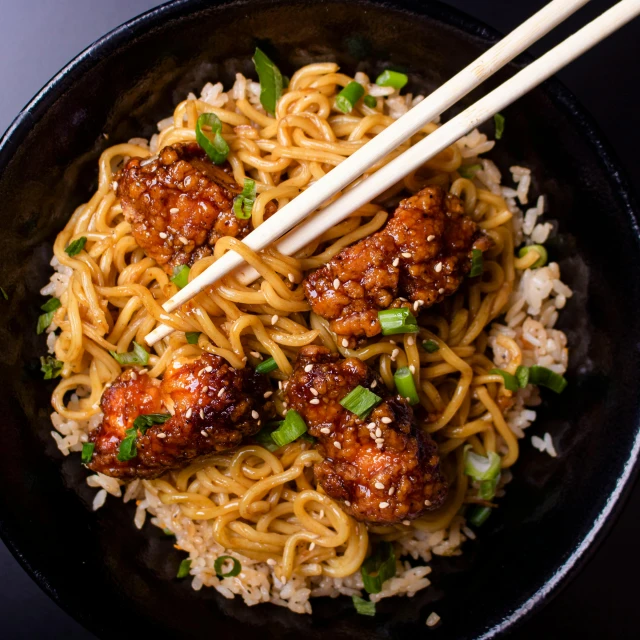 a meal is served with chopsticks in a black bowl