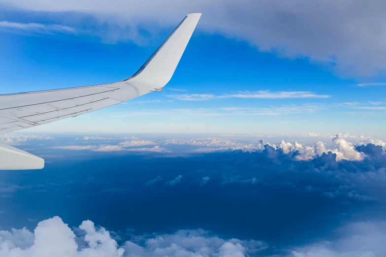 an airplane wing flying over some clouds in the sky