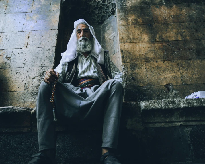 an old man in turban sitting down in a doorway