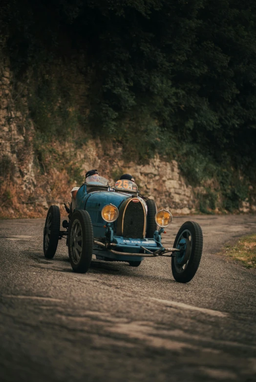 a small vintage blue car drives on the street