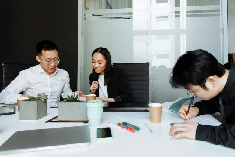 three business people sitting at a table working on paperwork