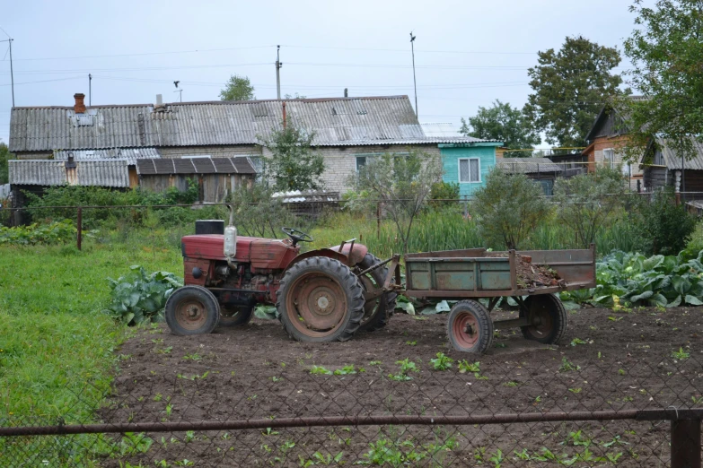 an old tractor parked on a farm with a load attached