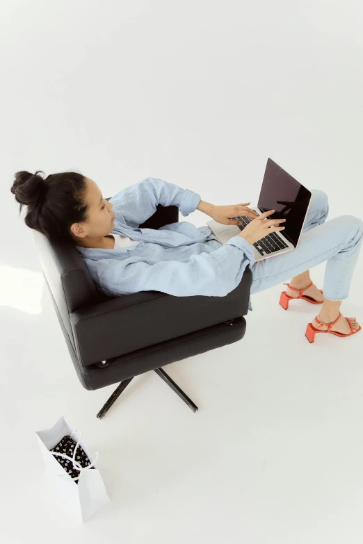 woman lying on chair with her laptop in hand