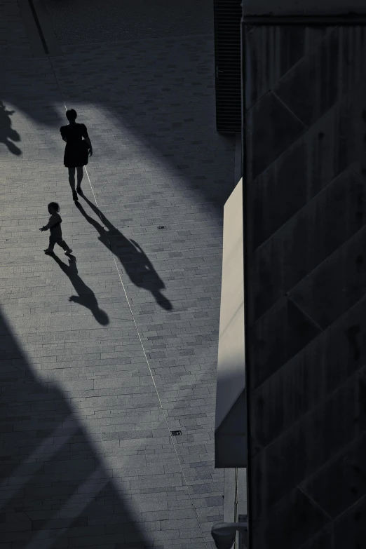 two people on the pavement walking with their shadow