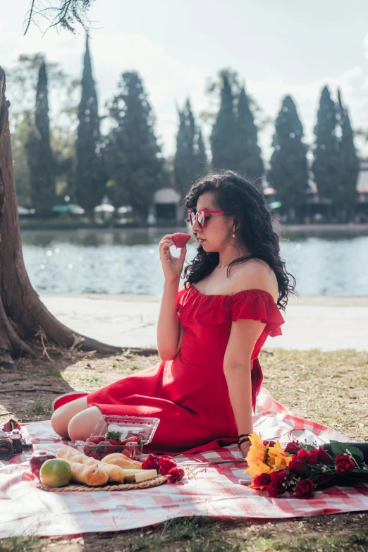 a woman sitting in the grass by a body of water