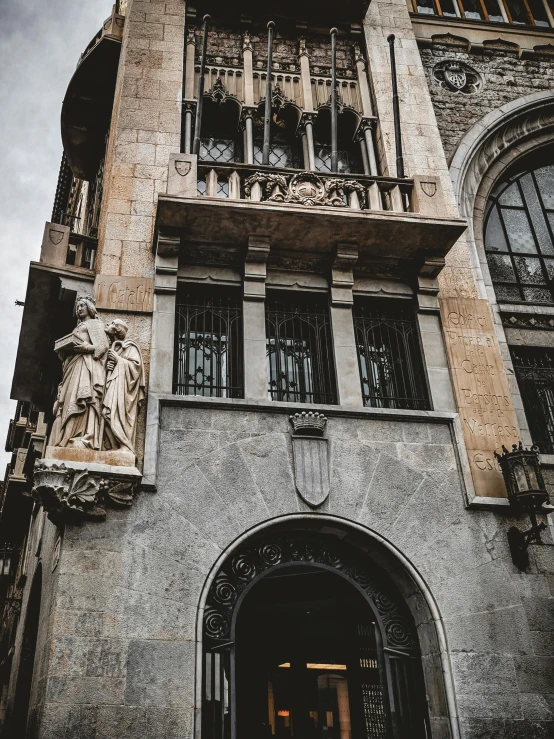 an old grey building has statues on the balconies and a stone clock