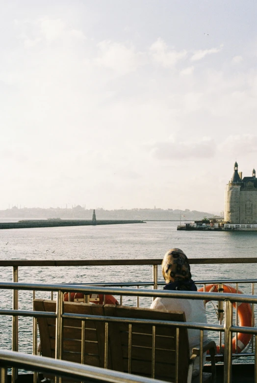 the person is sitting on a bench watching water