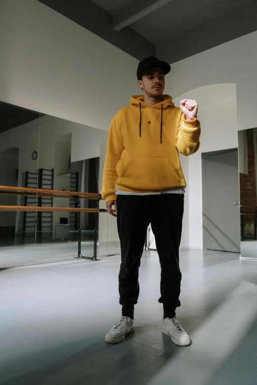 a young man with a yellow hoodie stands in the middle of a room