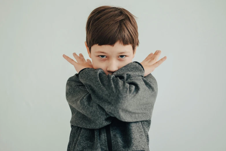 a little boy covering his face with his hands