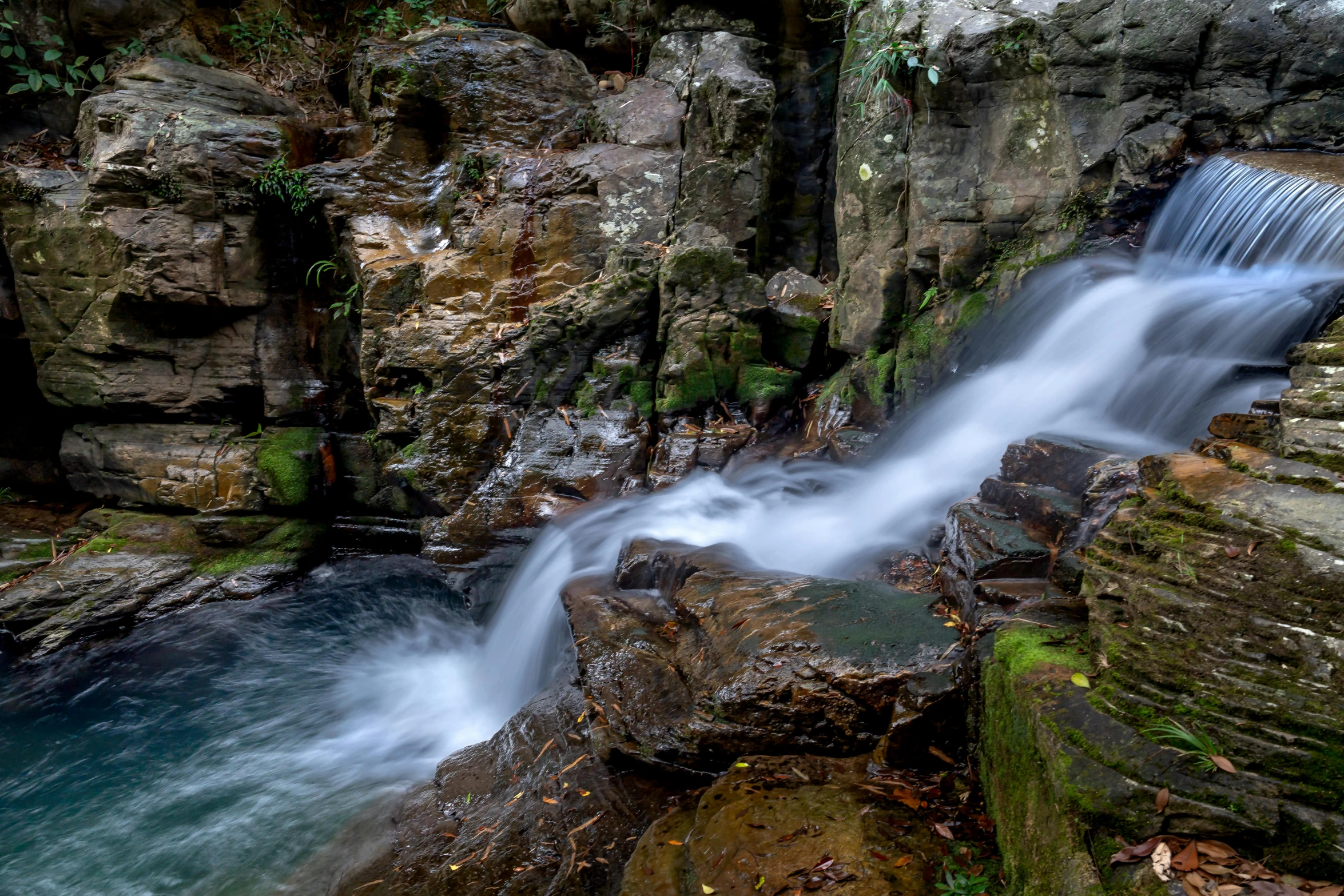 water flowing down some rocks near a large waterfall