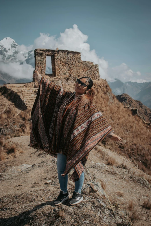 woman standing on a mountain with her shawl over her shoulders