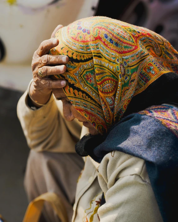 a woman wearing a multicolored hat sitting down