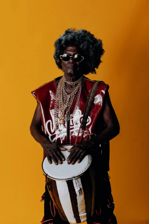 man with black hair wearing a tank top, holding a congas