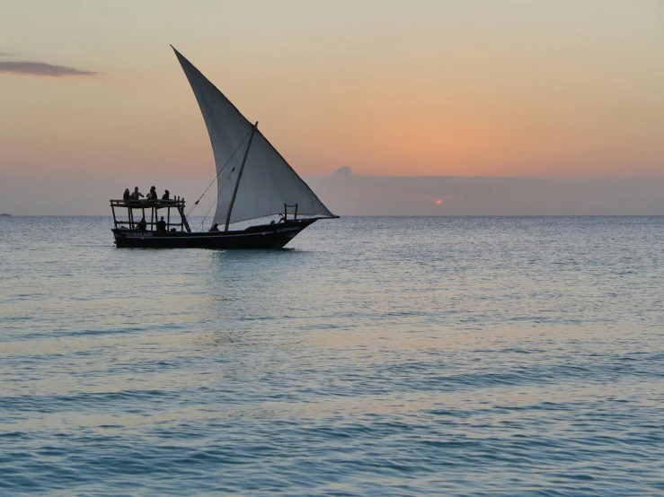 a boat is sailing on the ocean as the sun sets