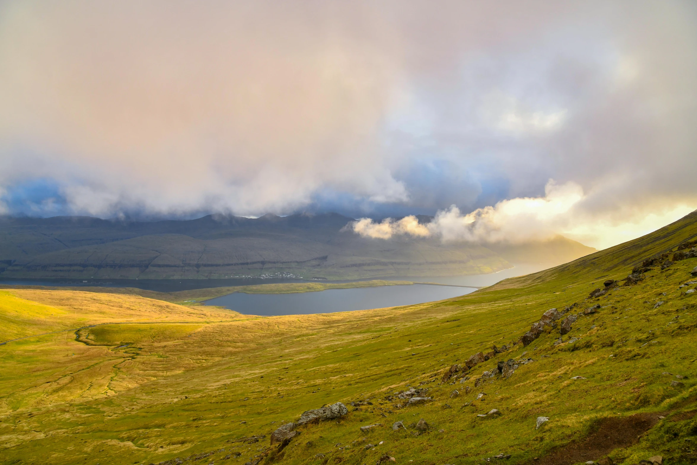 some water clouds rolling in the background and a green grassy hill