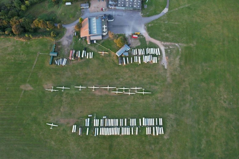 the airplane is flying over the grass near a parking lot