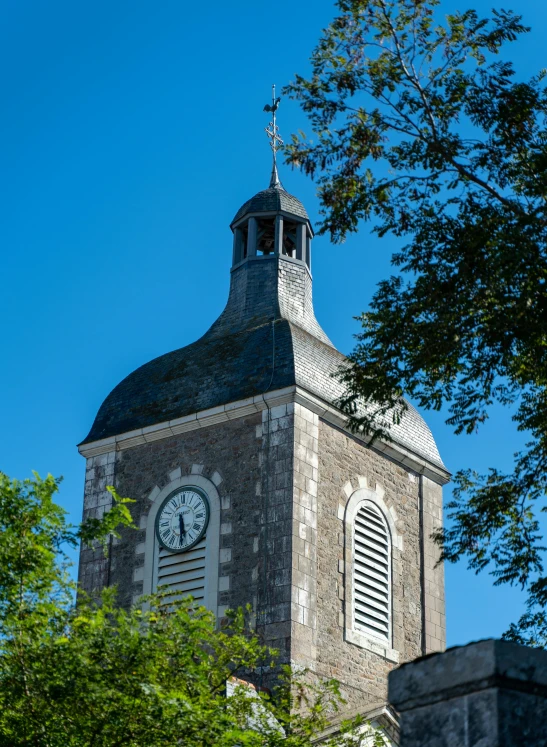 an old stone church clock tower with trees in front of it