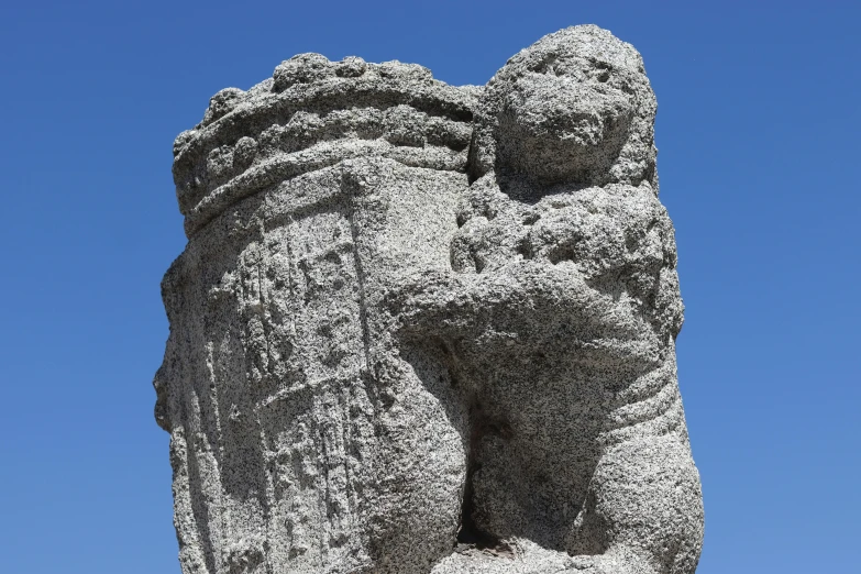 a carved stone bear sits in front of the clear blue sky
