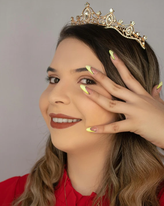 a beautiful woman with gold fingernails wearing a tiara