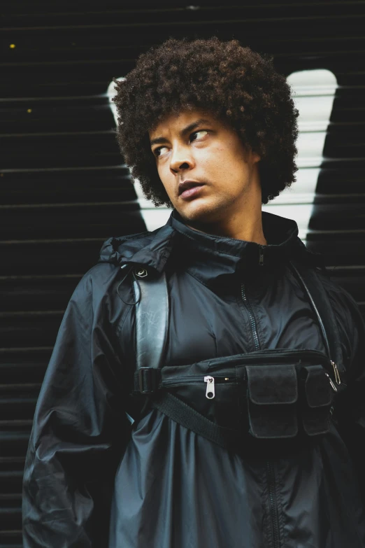 a man with an afro standing in front of a wall