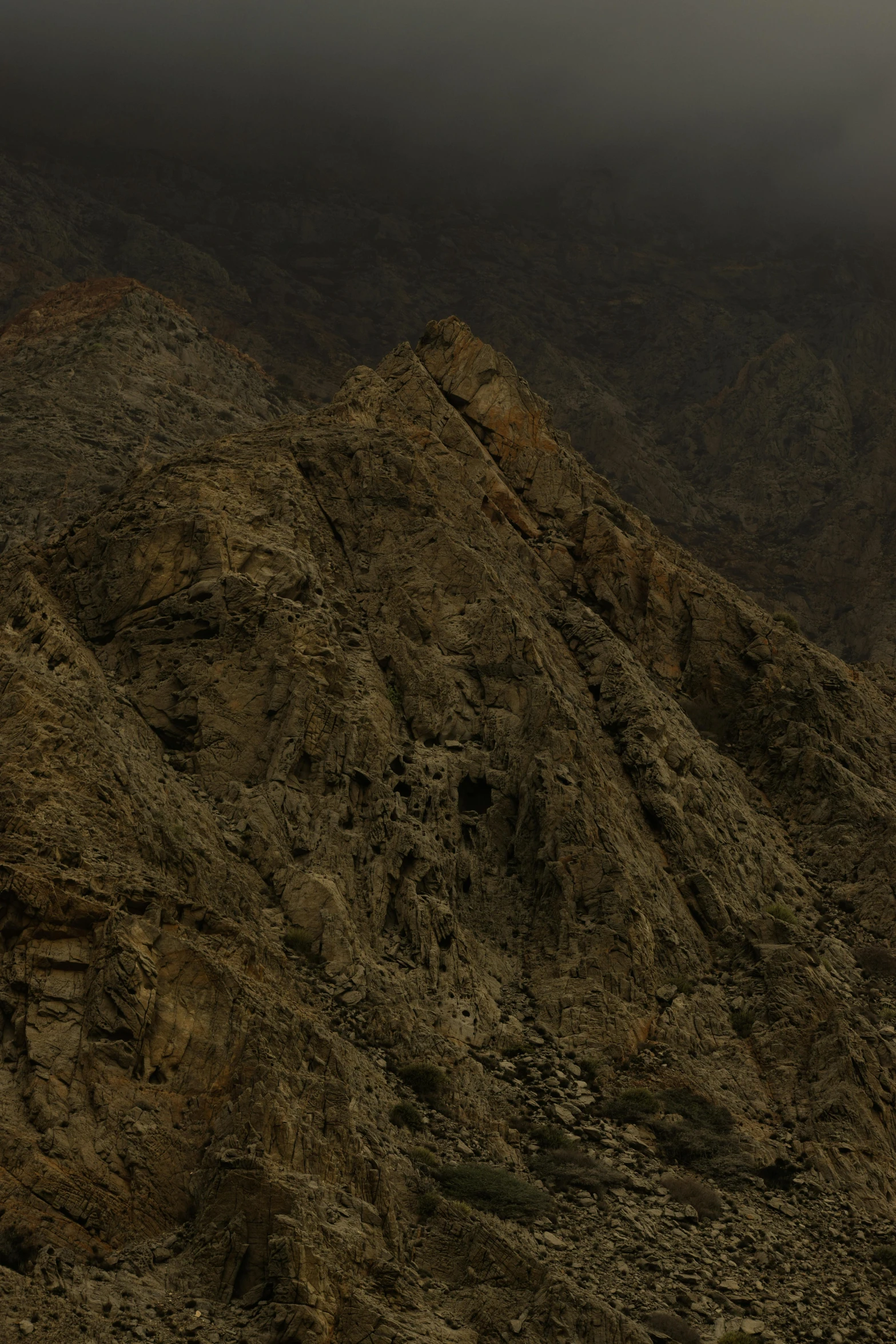 a dark mountain with the moon behind it