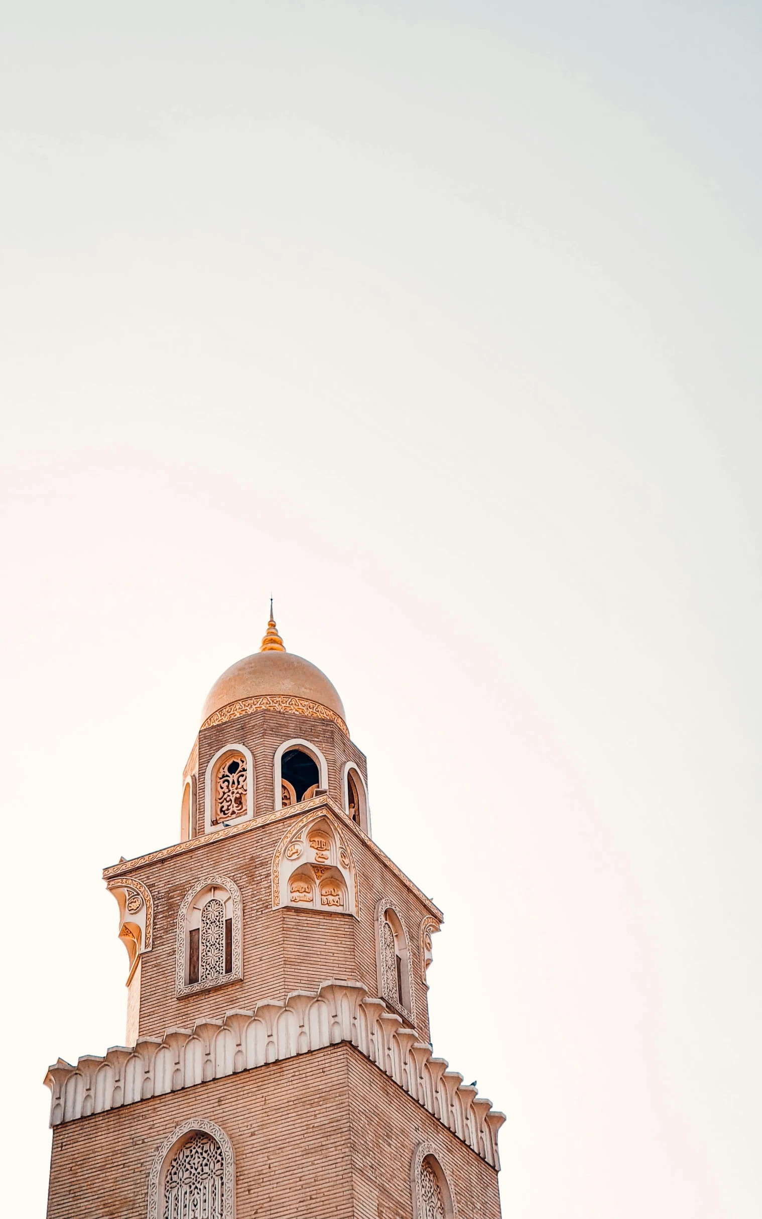 an ornate clock tower stands against the pale blue sky